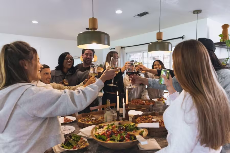 Friends raising a toast around a kitchen island covered with food.