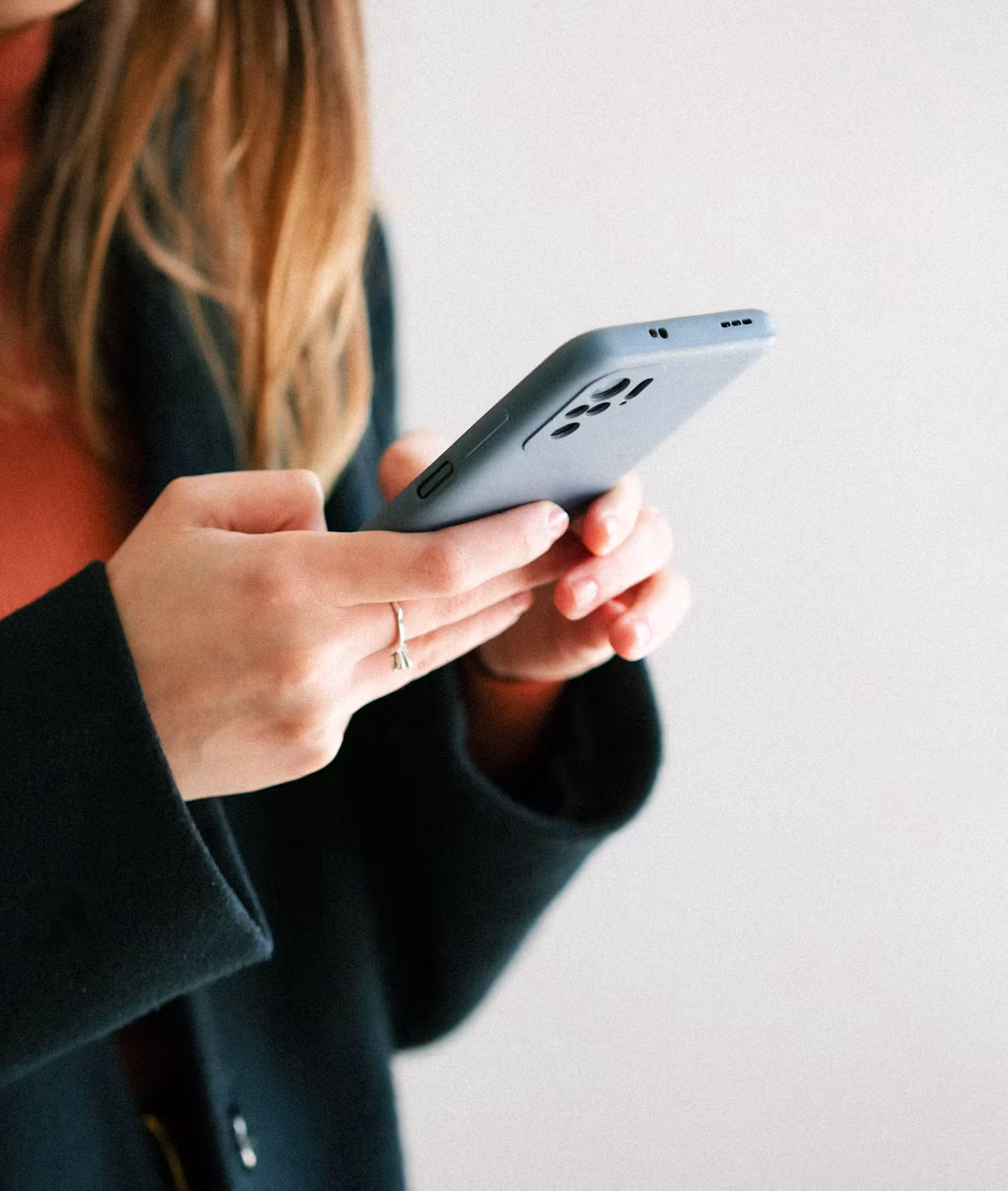 A woman holding her phone in both hands, typing a message.
